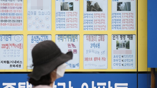 한 시민이 부동산 매물정보가 붙어 있는 공인중개업소 앞을 지나가고 있다. <연합뉴스>